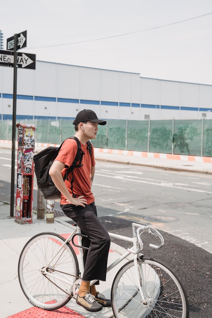 Man with a bike waits at a city crossroad, embodying urban street style.